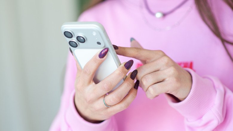 A woman in a pink sweater using an iPhone 17