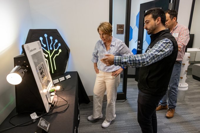 A man and woman talking before an electrical device.