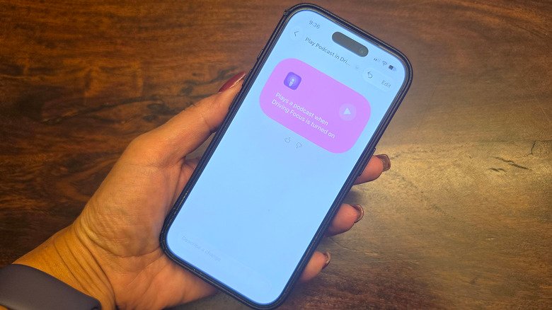 A hand holding an iPhone, showing Driving focus mode with an automation.