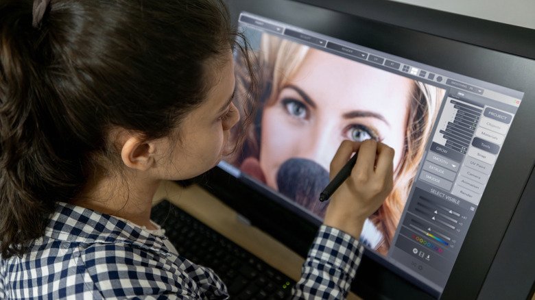 A person editing an image on a computer screen using a stylus.