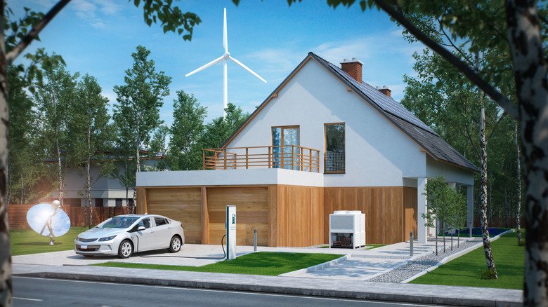 An EV charging in the driveway of a residential home, with a wind turbine in the background.